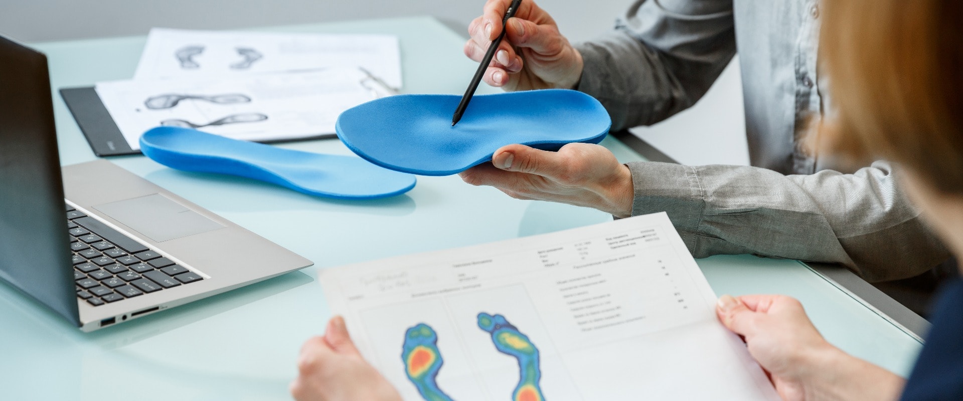 Doctor consulting patient on custom orthotic insoles in a clinic for a personalised custom fit.