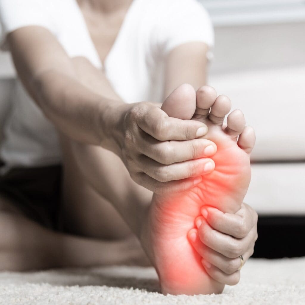 Foot pain, Asian woman feeling pain in her foot at home, female suffering from feet ache use hand massage relax muscle from soles in home interior, Healthcare problems and podiatry medical concept